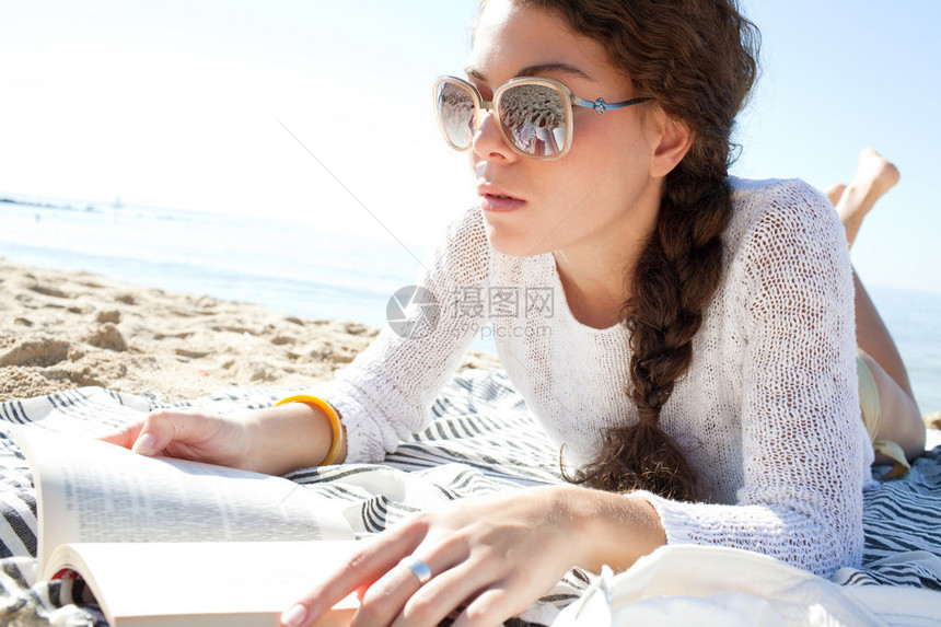 一个美丽的年轻女子在海滩上放松和晒日光浴图片