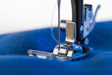 工作缝纫机缝制蓝色织物的特写视图图片