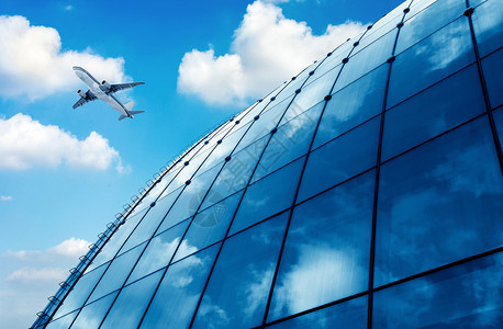 蓝天下的玻璃幕墙和飞机图片
