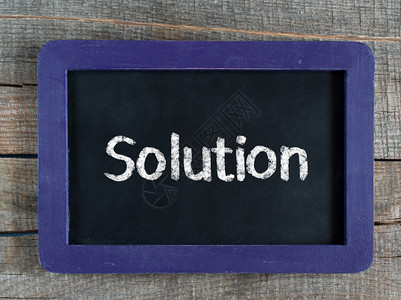 解决方案标题字写在木制背景上的蓝色框架黑板上图片