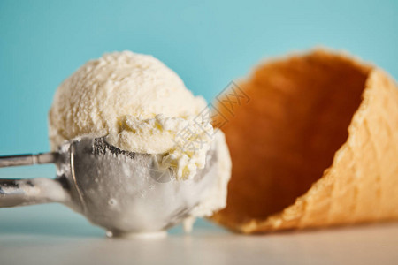 勺子里的美味冰淇淋勺和蓝色的华夫蛋筒背景图片