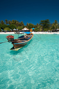 漂浮在完美水晶般清澈的蔚蓝海水中的传统泰国长尾船的特写镜头图片