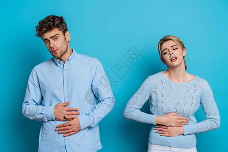 男人和女人在患蓝底腹部疼痛时触摸肚子同图片