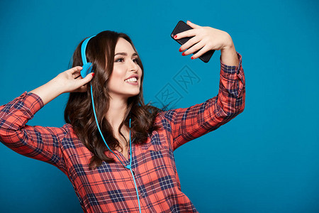 美丽的年轻女子通过耳机听音乐自图片