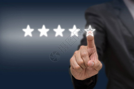 商人指着五星符号来提高公司或酒店在暗色调下的评级商业评价概图片