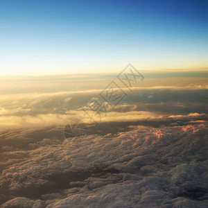 在云层上方飞行时多云日出的鸟瞰图图片