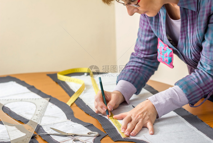 女裁缝用铅笔在桌子上画西装的裁缝图案图片