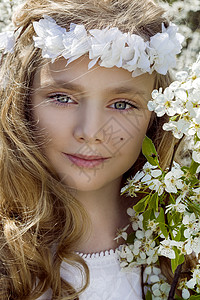花姑娘金发长的可爱小女孩站在花环的草地上背景