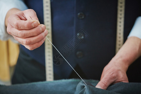 用针线缝制衣服的裁缝手图片