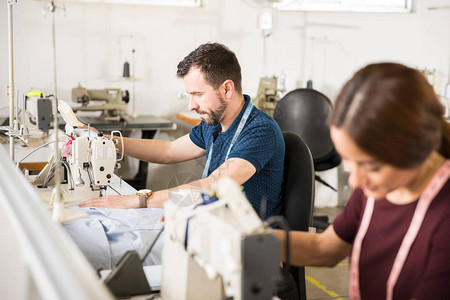 两个人坐在生产线上在纺织厂使用缝纫机图片