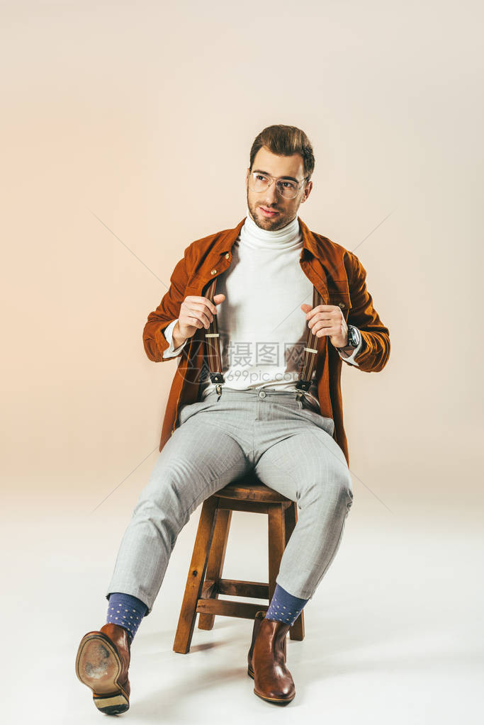 英俊帅的男人在坐木椅子上米色上坐图片