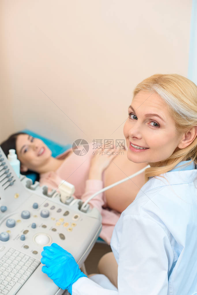 快乐成熟的妇产科医生为孕妇做超声检查图片