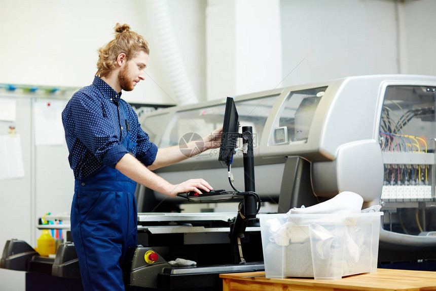 印刷工在厂使用印刷机图片