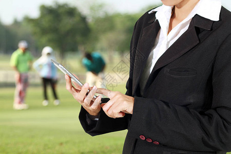 商人和女正在使用手机和触摸智能手机让高尔夫球手打扫并保持高尔夫球场图片
