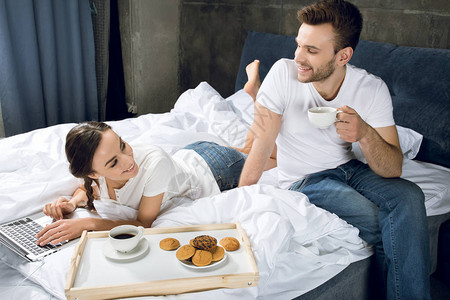 男子喝咖啡时妇女在床上使图片