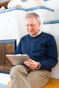 老人或养老金领取者坐在家里的炉前图片