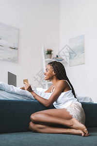 年轻非裔美国妇女在家里在卧室里做电子背景图片
