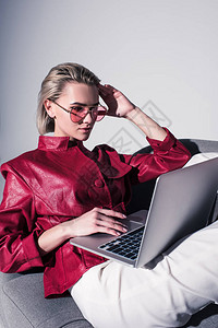 穿着红色太阳镜的漂亮时装女孩使用笔记本电脑图片
