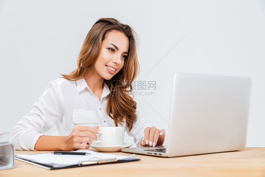 快乐的有吸引力的年轻女商人喝咖啡和白种背景使图片