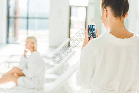 妇女用智能手机拍摄她在温泉中心图片