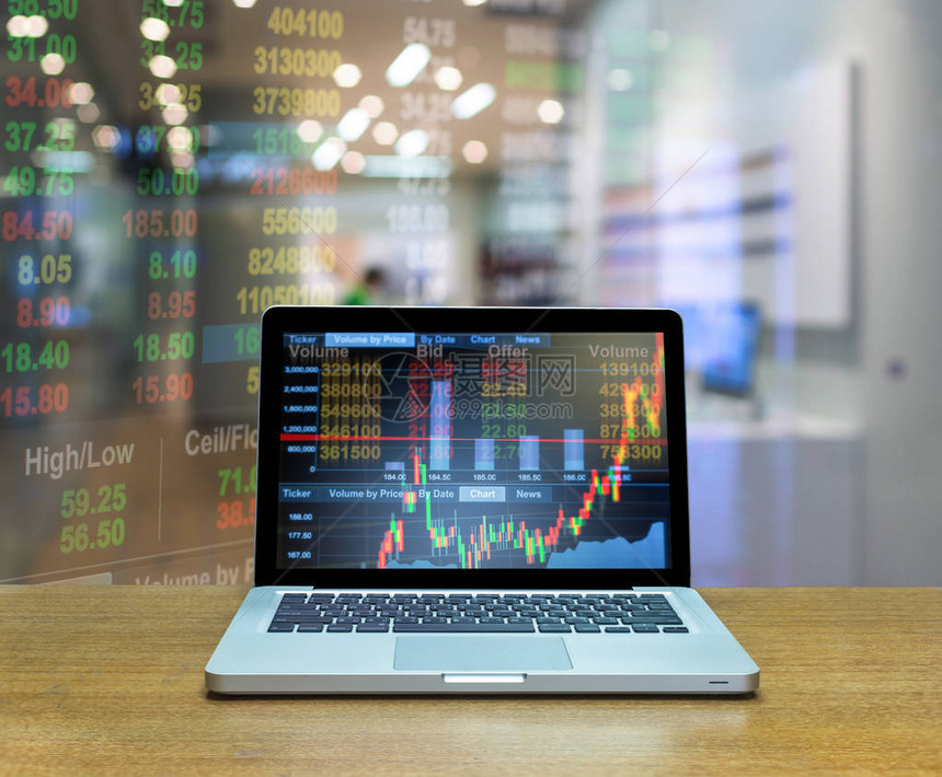 木桌上笔记本电脑屏幕上的证券交易所市场交易图