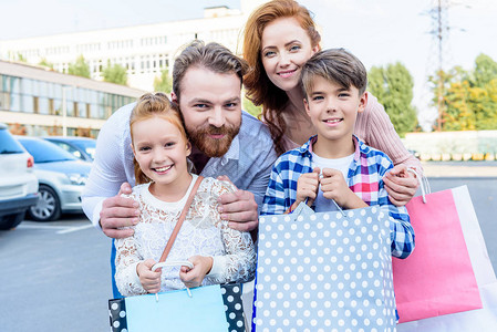购物后父母用购物袋抱孩子并站在图片