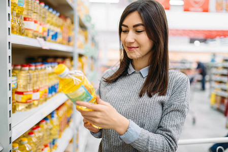 妇女在超级市家庭购物中选择向日葵花油的妇女图片