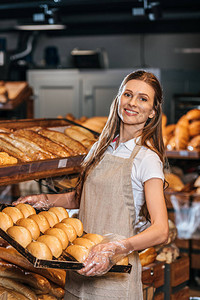 微笑的售货员在购物市场上安排面包图片