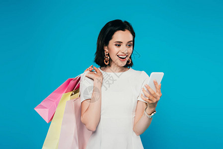 穿着便装的快乐优雅女人拿着手持智能手机的购物袋图片