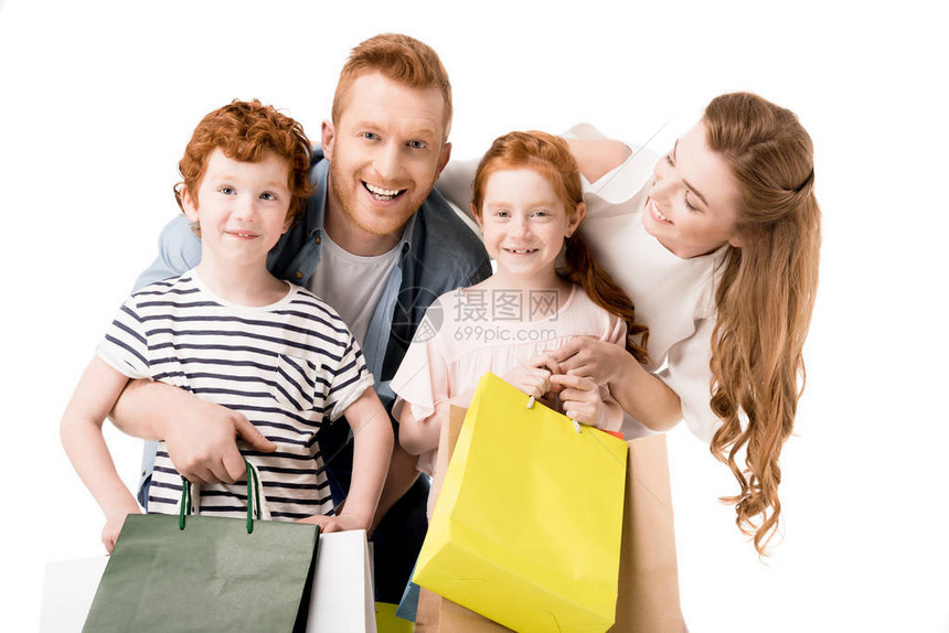 快乐的年轻家庭拿着购物袋微笑着被白色图片