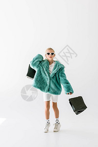 穿着绿色大衣和墨镜的可爱时髦孩子用白色孤立的图片