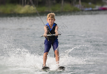 金发男孩在湖上滑水图片