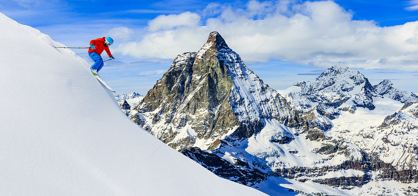 滑雪者在新鲜的粉雪中在高山滑雪下坡与马特宏峰的雪山脉在中采尔马特阿尔图片