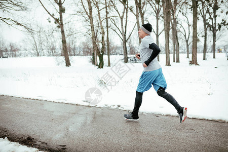 参加冬季训练的高级活跃男子在公共园跑步和锻炼图片