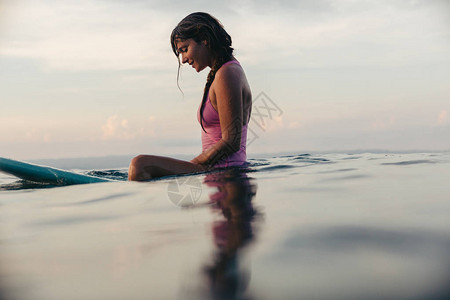 日落时坐在水中冲浪板背景图片