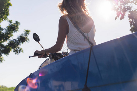 女骑摩托车与冲浪板对着蓝背景图片