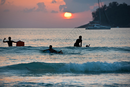 日落时男孩在海边冲浪板上冲浪的剪影图片