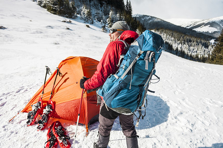冬天在帐篷附近的人极端条件下的游客雪鞋登山杖和背包在冬季山区露营雪地图片