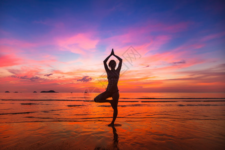日落时在海边练习瑜伽的女人的剪影图片