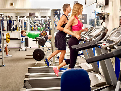 男人和女人在带的健身房的跑步机上跑步图片