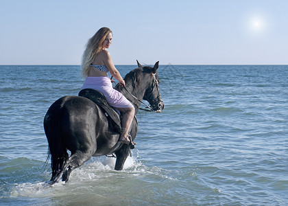骑马的女人和她的种马在海中骑行图片