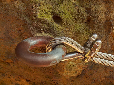 镀铬螺丝扣钩和索环的细节用螺丝卡钩固定在一起的铁绞绳锚固在砂岩石图片