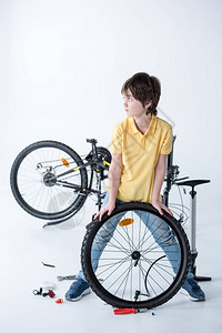 在白色工作室修理自行车轮胎的小男孩背景图片