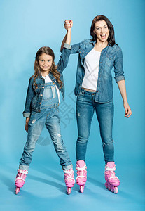 穿着溜冰滑雪鞋的妈和女儿在隔着蓝色的摄图片