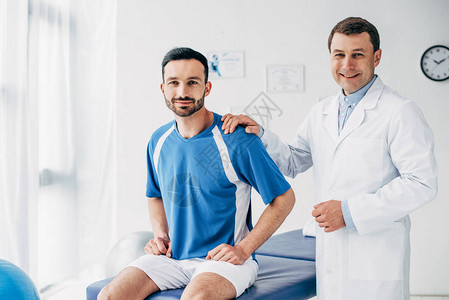 带着微笑的生理治疗师和橄榄球运动员在医院图片