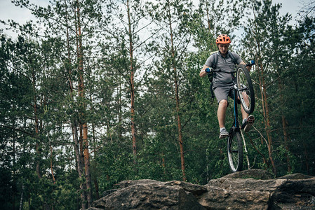 戴防护头盔的男骑自行车男子在森林中对山骑脚踏车特图片