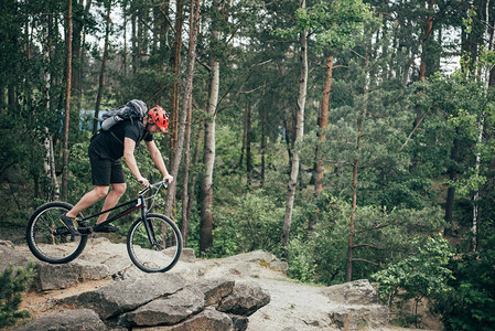 保护头盔在森林里骑山脚踏车时特技的男极图片