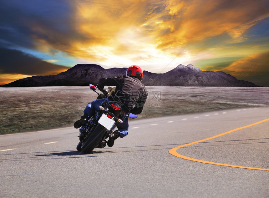 从农村和山区背景看青年男子骑摩托车在沥青公路曲线上行图片