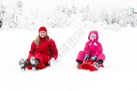 妈和她的小女儿在雪地里带着鲍勃背景图片