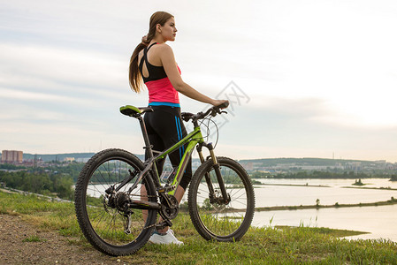 一位骑山地自行车的女自行车手看着河流的风景骑自行车冒险旅行生活图片